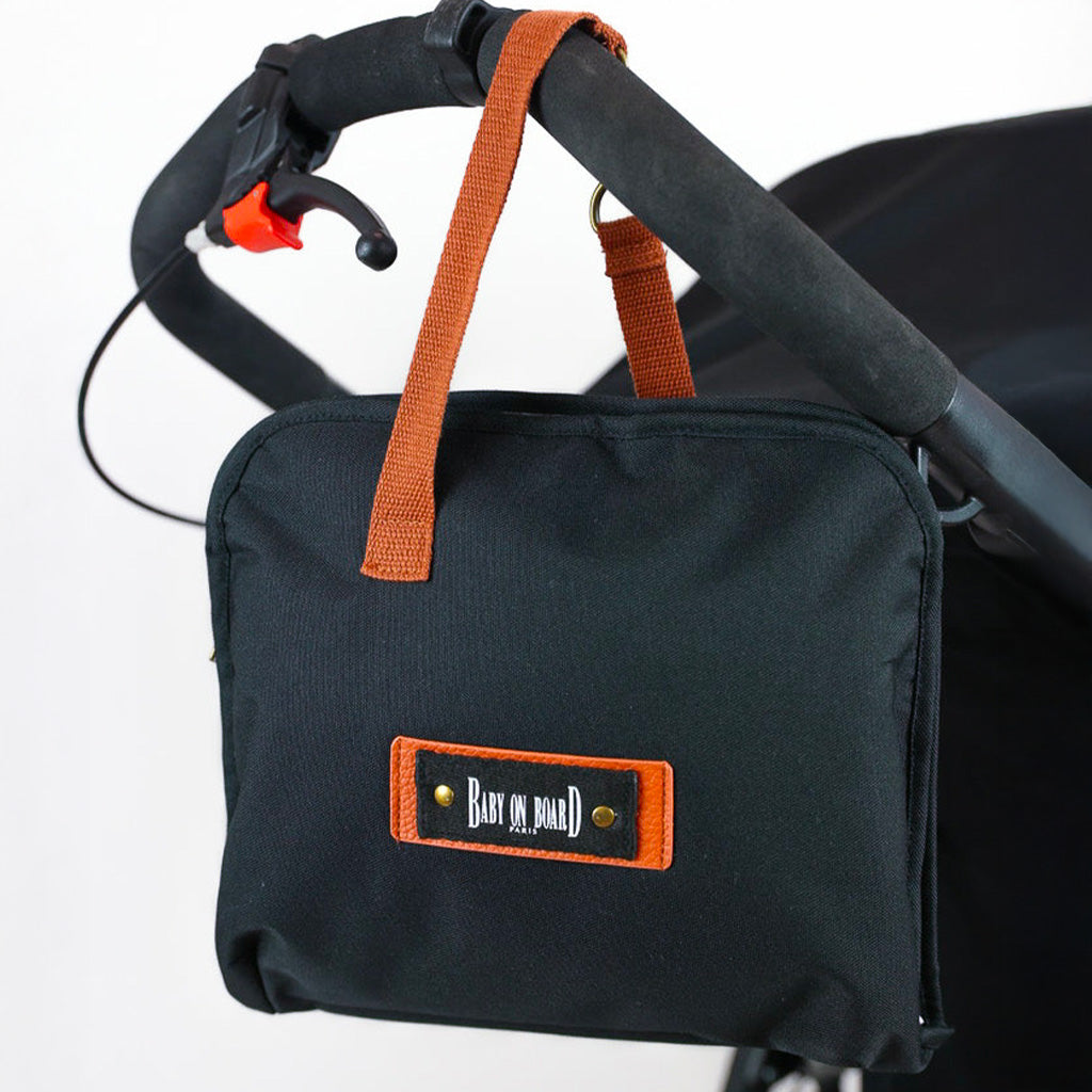 Mini sac à langer Miniz Pouch Black Baby on Board fixé à une poussette, parfait pour transporter le nécessaire de bébé tout en gardant les mains libres.