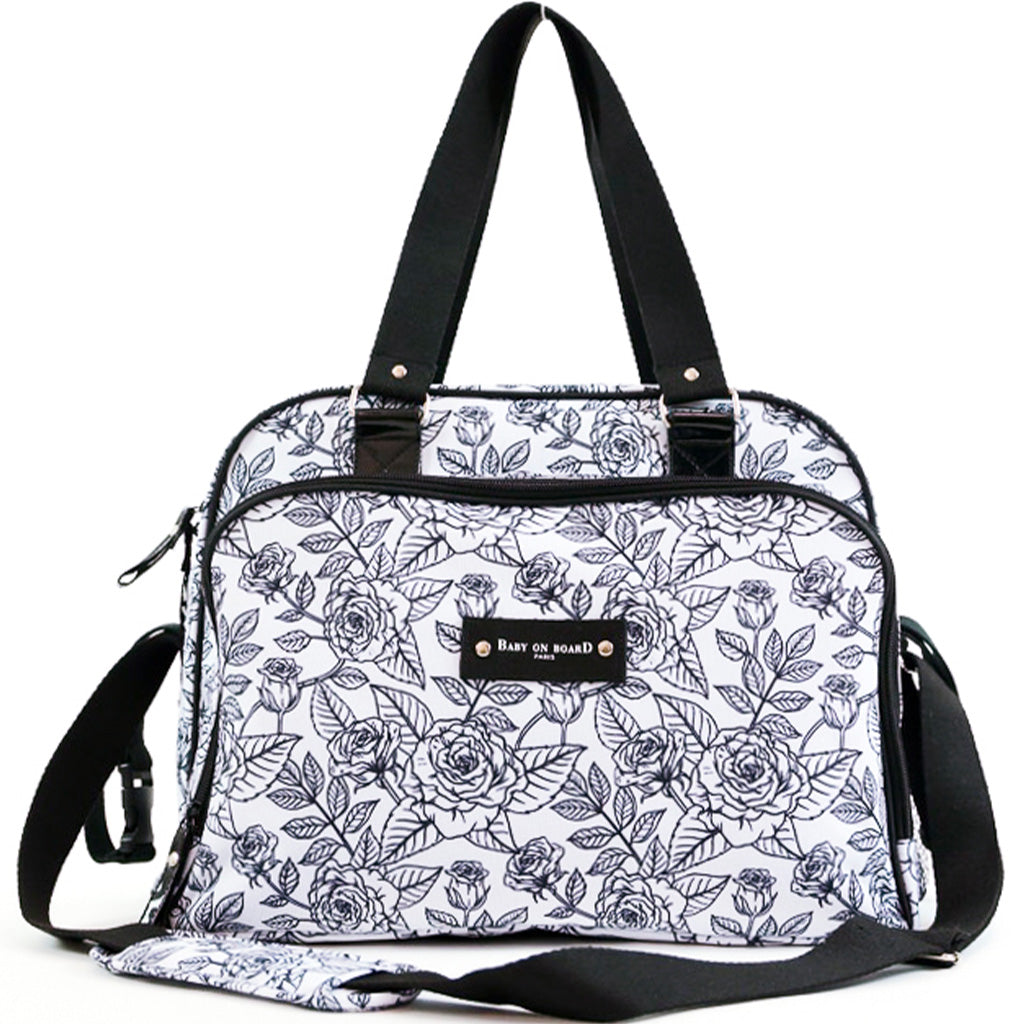 Sac à langer Simply Rose avec imprimé floral noir et blanc, doté d'une bandoulière ajustable et de poignées renforcées.
