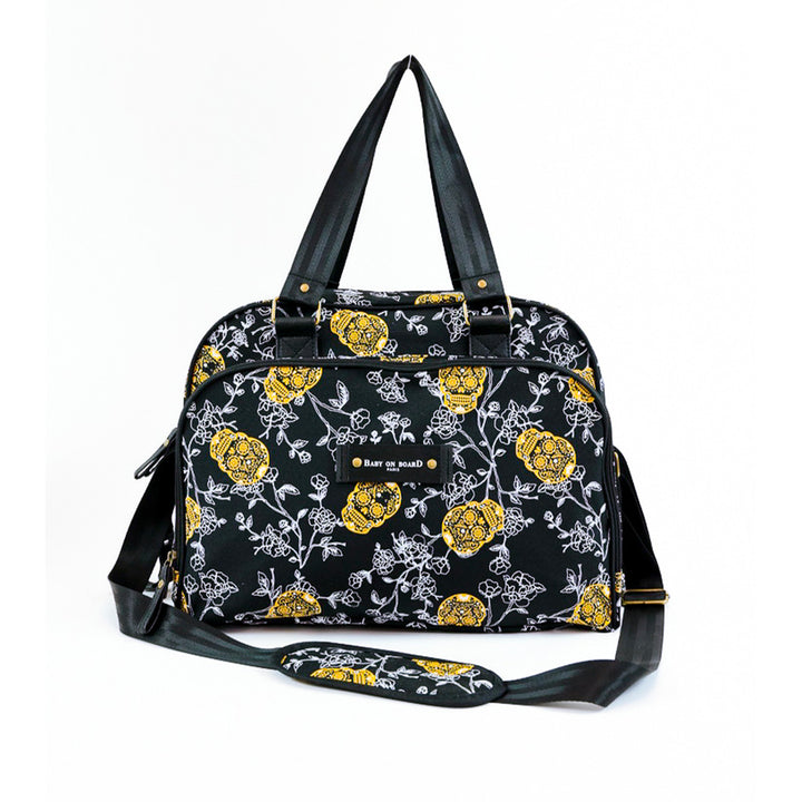 Sac à langer Simply Skull Look Baby on Board noir avec imprimé floral et têtes de mort dorées, un design audacieux et pratique pour les parents modernes.