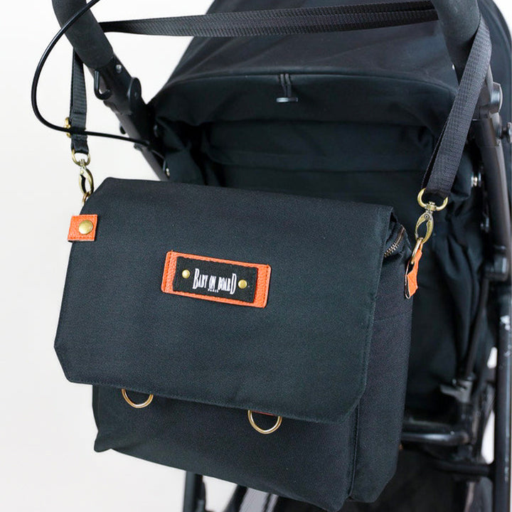 Sac Smart Organiz Black attaché à une poussette, illustrant sa praticité pour les sorties avec bébé.
